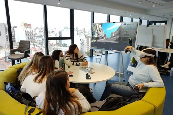 Un grupo de estudiantes alrededor de una mesa; una de ellas usa un visor de realidad virtual.